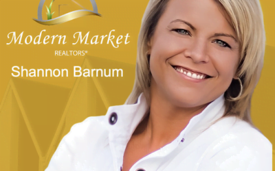 Shannon Barnum of Modern Market REALTORS® smiling in front of a gold background with logo and name, representing trusted real estate services in Fargo-Moorhead.