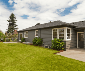 Single-story gray suburban home with a well-maintained lawn, bay windows, and a concrete patio, located in Dilworth, MN.