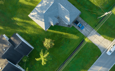 Aerial view of a suburban home with a long driveway and surrounding green lawns in a residential neighborhood