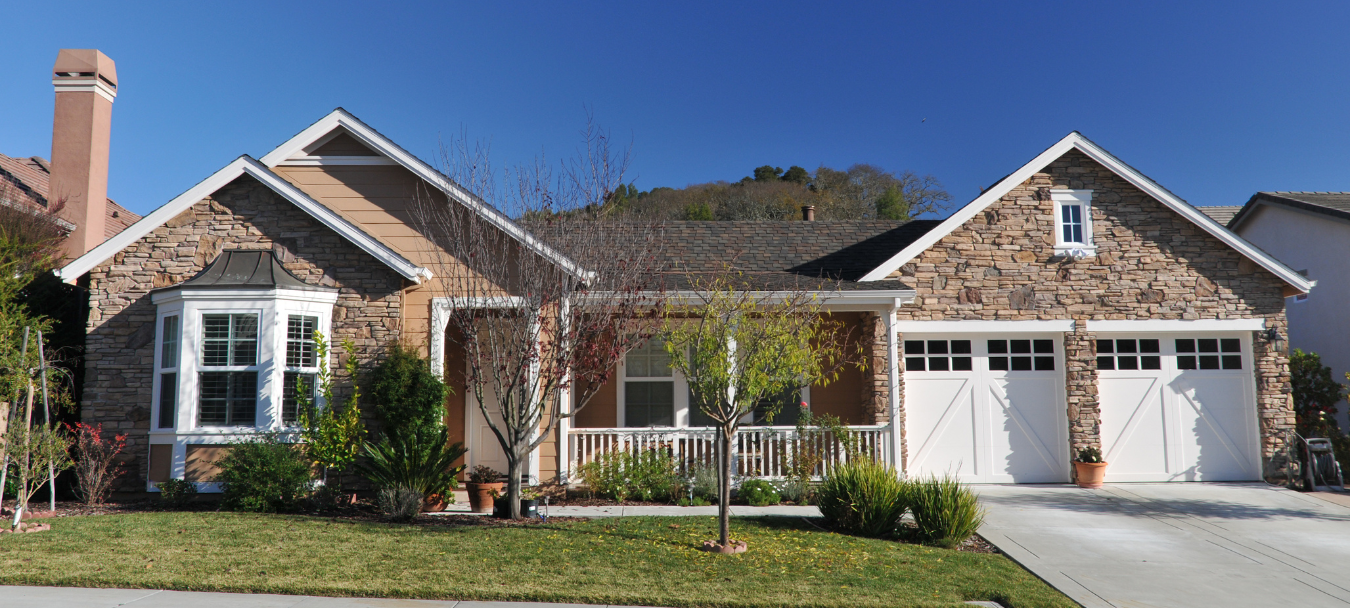 Single-story suburban home in Horace, ND with stone façade, front porch, and attached three-car garage under a clear blue sky.