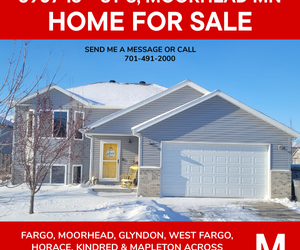 Exterior of a bi-level home for sale at 3907 13th St S in Moorhead, MN, featuring a two-stall garage, yellow front door, and winter setting.